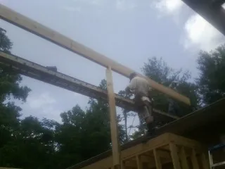 Carpenter setting a ridge beam over a new addition frame — Ice Dam Removal by Roofing Brothers in Thaxton