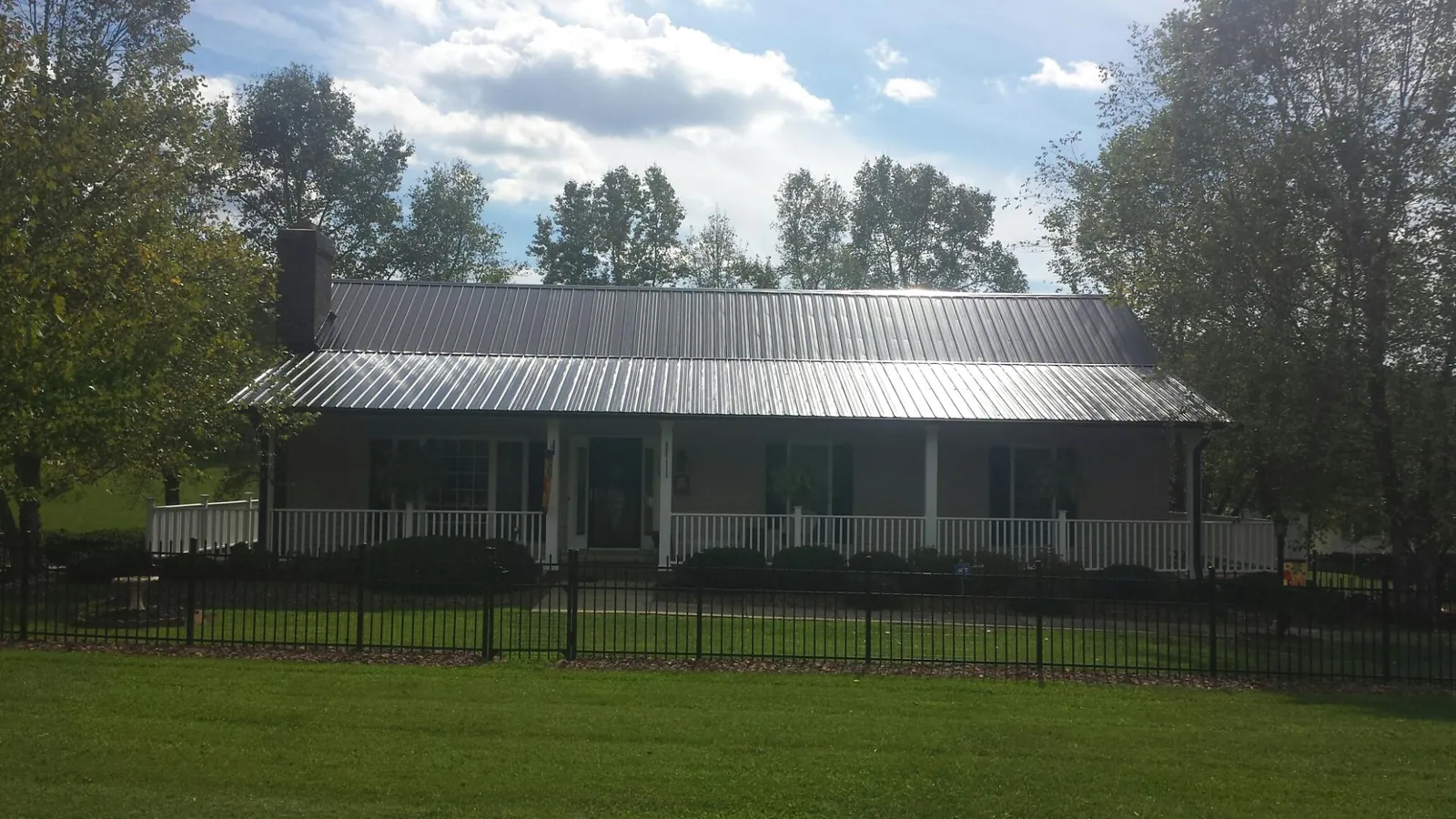 Gray metal roof on a brick ranch with a full width front porch — Gutter Guard Installation work by our crew in Thaxton